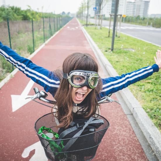 En pige på cykel med pilotbriller på