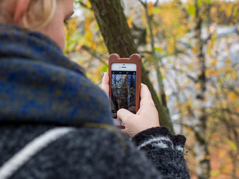 Pige der tager billeder med sin mobil i naturen